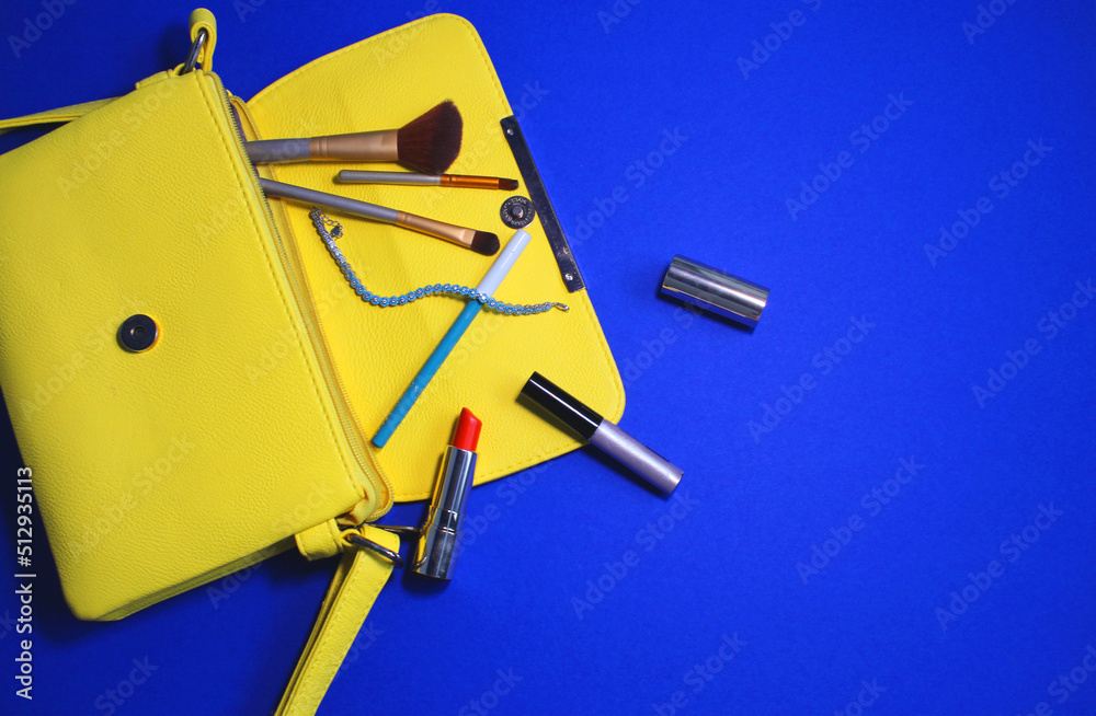on a blue background, a yellow handbag with cosmetics