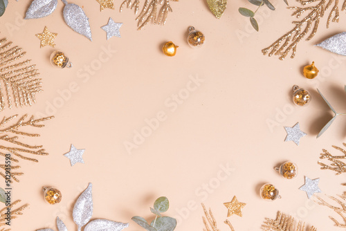 christmas or new year frame composition. christmas decorations in gold colors on pastel beige background with empty copy space for greeting