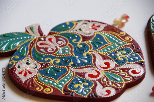 Handpainted apple with intricate ornate pattern, made from wood, painted with acrylic colors. Ornamental design on a red background.