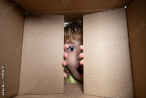 Fotografía Child boy opening a carton box and looking inside, unpacking concept, surprise unboxing