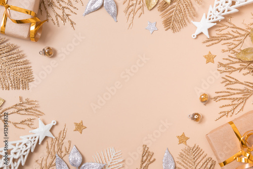 Christmas festive background from twigs and leaves of golden glitter on pastel beige. Empty copy space for greeting text