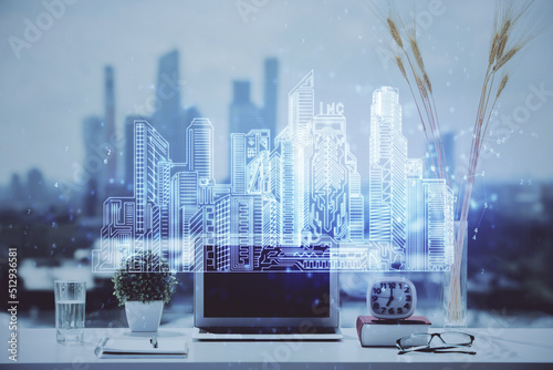 Desktop computer background in office and big town buildings hologram drawing. Double exposure. Smart city concept.