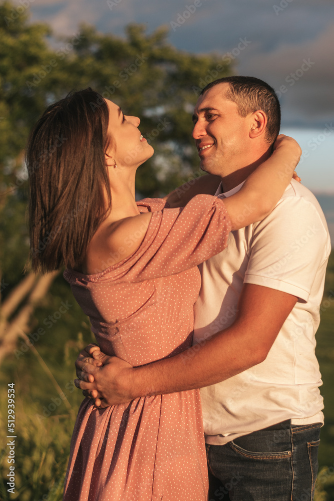 A couple of lovers man and woman hugging and kissing in a meadow at sunset.Love,passion,youth,happiness,summer concept. A couple of lovers man and woman hugging and kissing in a meadow at sunset.Love,passion,youth,happiness,summer concept.