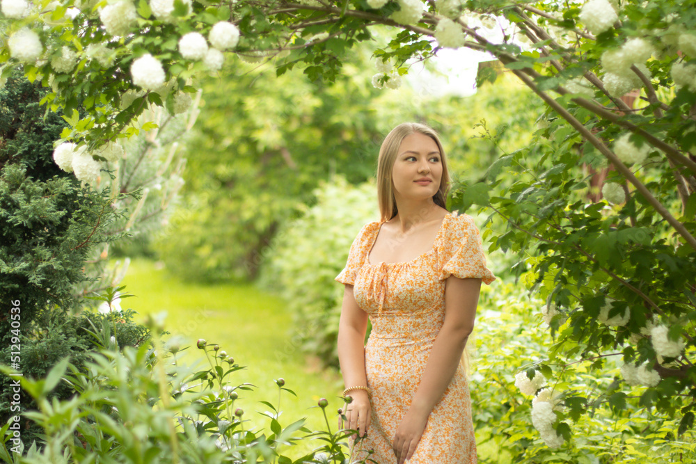 Young Slavic blonde girl with long hair on the background of blooming viburnum Boule de Neige Young Slavic blonde girl with long hair on the background of blooming viburnum Boule de Neige