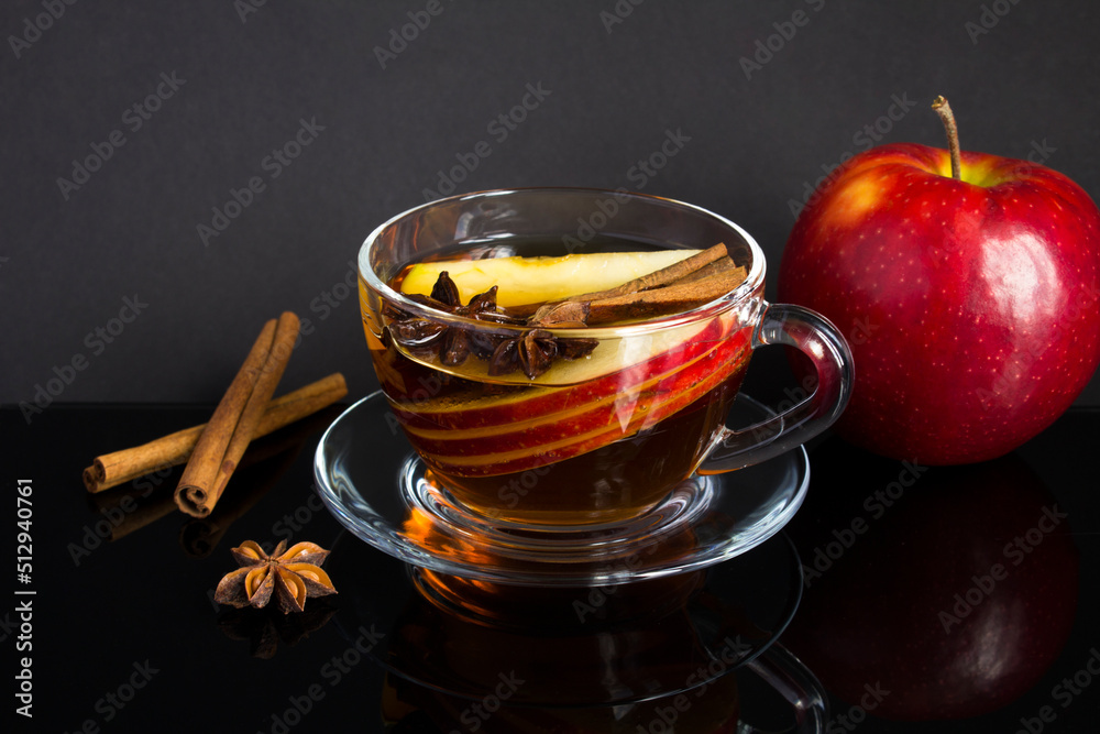 Tea with apple, cinnamon and anise in the glass cup on the black background. Closeup. Tea with apple, cinnamon and anise in the glass cup on the black background. Closeup.