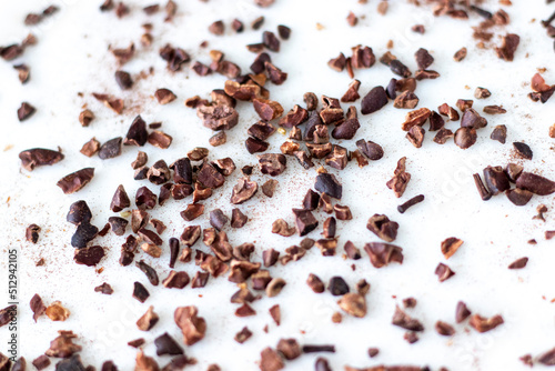 Crushed cacao beans on white background. Selective focus.
