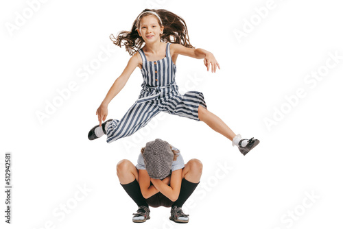 Happy school age kids wearing retro clothes playing leapfrog isolated over white background. Concept of childhood, vintage summer fashion style