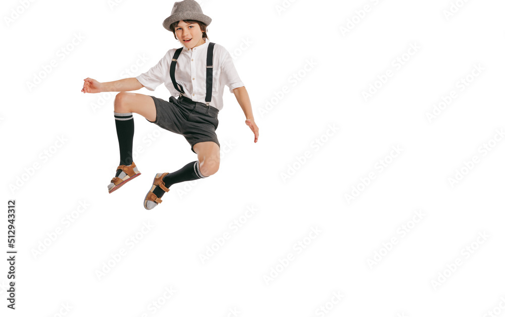 One happy smiling boy, kid in retro style outfit, fashion of 70s, 80s years jumping isolated on white studio background with copyspace for ad.