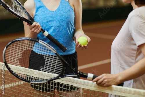 Close-up of unrecognizable women with racquets standing at tennis net and choosing who will pitch tennis ball © Mediaphotos