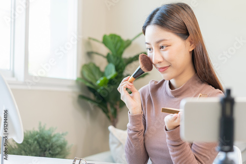 Beauty blogger  asian young woman  girl vlogger makeup face  showing  reviews cosmetics products while recording video  tutorial to share on social media. Business online influencer on smartphone.