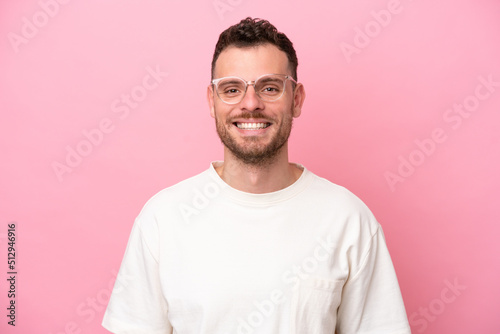 Young brazilian man isolated on pink background With glasses with happy expression