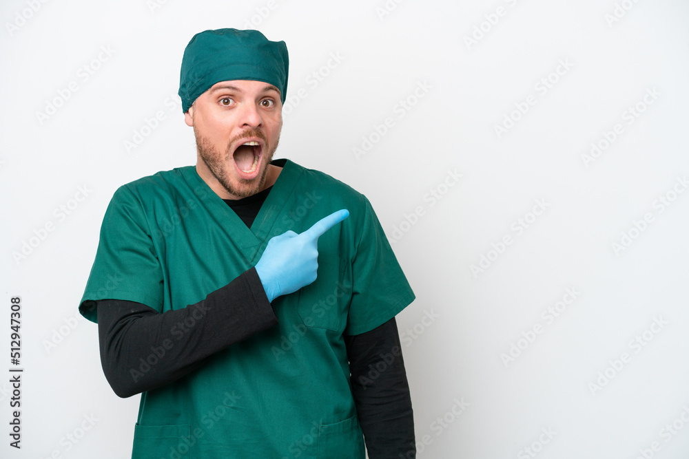 Surgeon Brazilian man in green uniform isolated on white background surprised and pointing side Surgeon Brazilian man in green uniform isolated on white background surprised and pointing side
