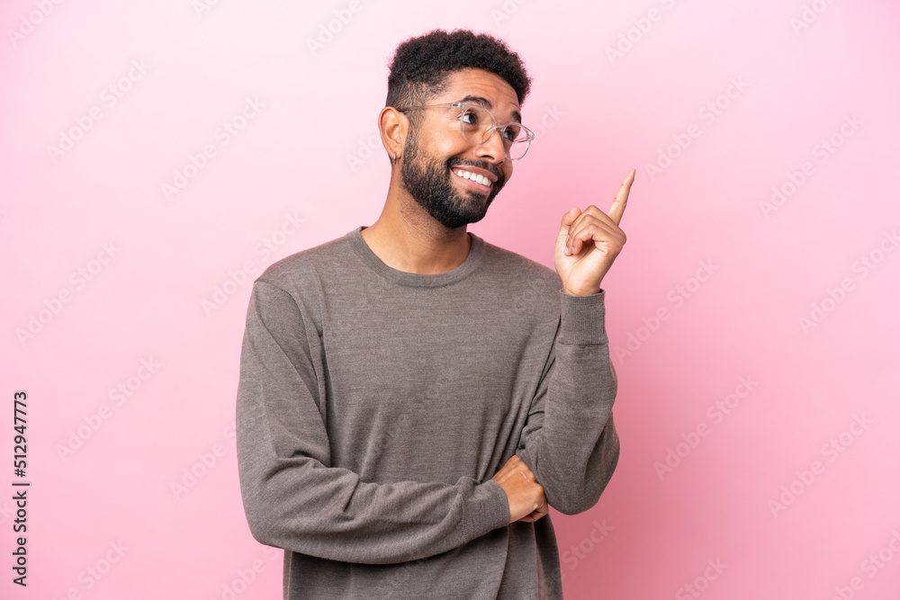 Young Brazilian man isolated on pink background pointing up a great idea Young Brazilian man isolated on pink background pointing up a great idea