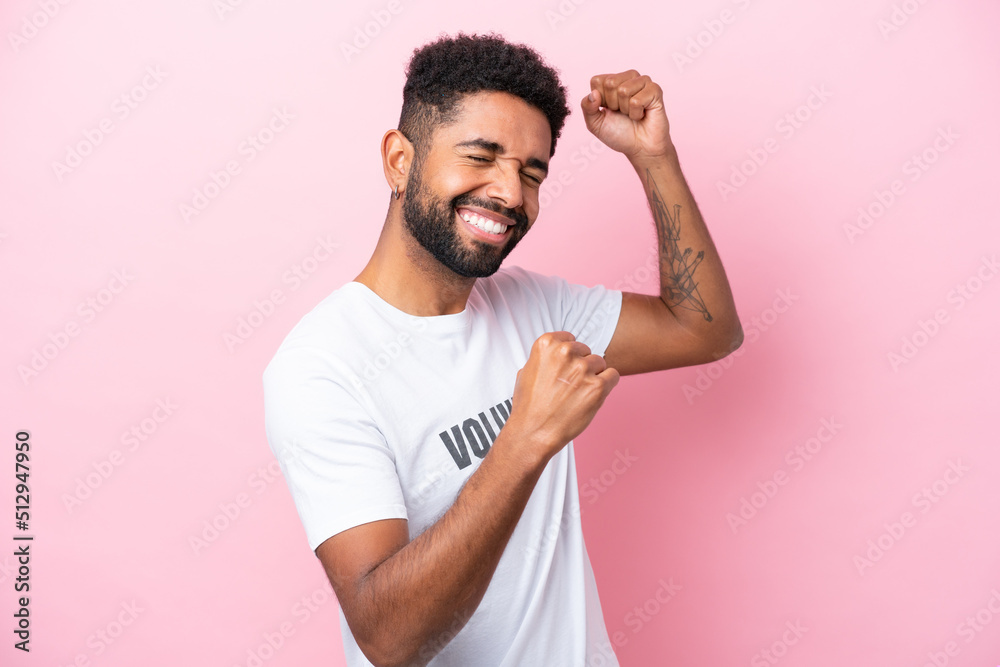 Young volunteer man isolated on pink background celebrating a victory Young volunteer man isolated on pink background celebrating a victory