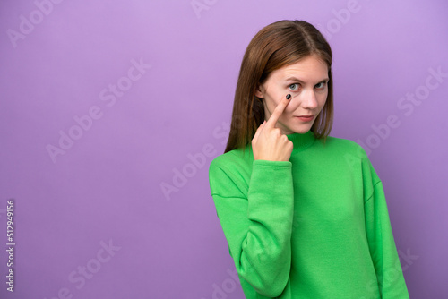 Young English woman isolated on purple background showing something © luismolinero