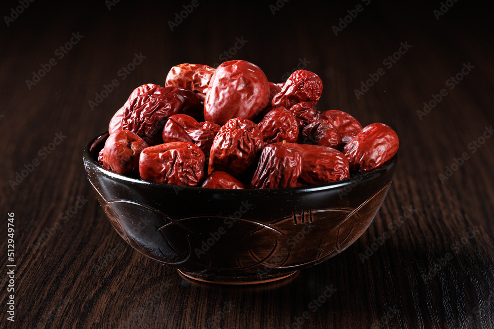 Dried red Chinese dates in a clay bowl on a black background. Dried red Chinese dates in a clay bowl on a black background.