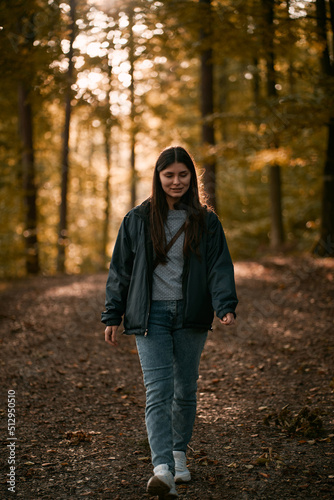 Woman is walking in the autumn forest. Strolling alone in the woods in September.