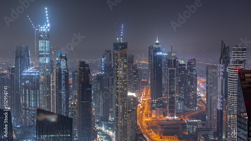 Downtown skyline with modern architecture form above night timelapse. Aerial view of Dubai business bay towers.