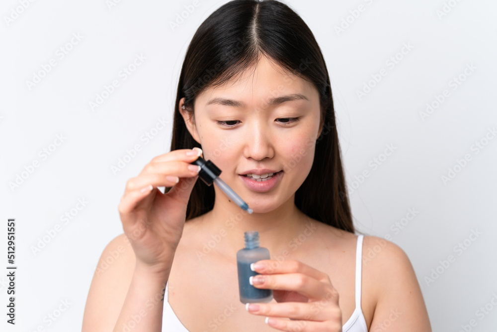 Young Chinese woman isolated on white background holding a serum while smiling. Close up portrait Young Chinese woman isolated on white background holding a serum while smiling. Close up portrait