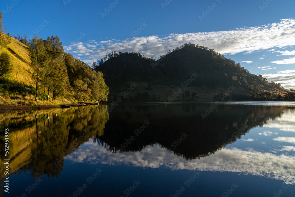 High resolution stitched panorama of a beautiful mountain summer view with reflections in a lake at the famous Kumbolo lake, Semeru mountain, East Java, Indonesia