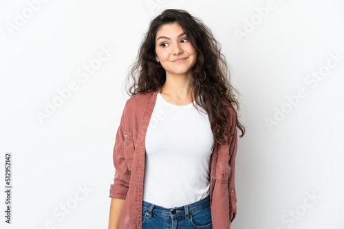 Teenager Russian girl isolated on white background making doubts gesture looking side © luismolinero