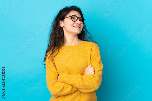 Teenager Russian girl isolated on blue background looking up while smiling