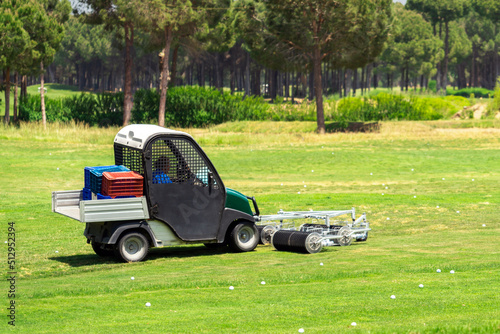 Golf course and a vehicle collecting golf balls. Ballpicker on driving range of golf club photo