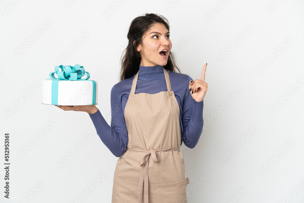 Pastry Russian chef holding a big cake isolated on white background thinking an idea pointing the finger up Pastry Russian chef holding a big cake isolated on white background thinking an idea pointing the finger up