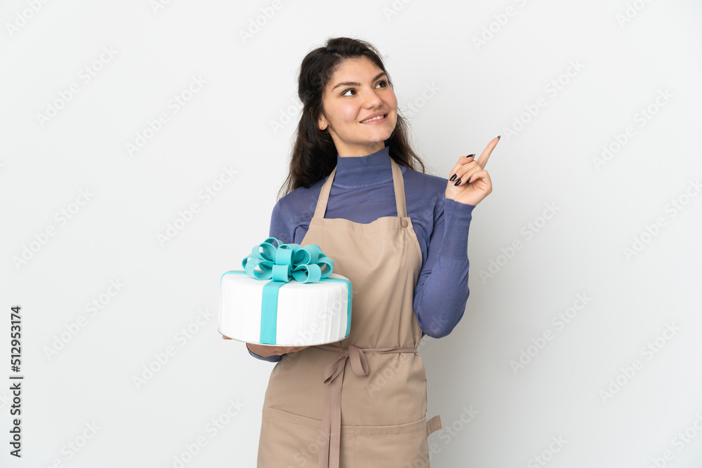 Pastry Russian chef holding a big cake isolated on white background pointing up a great idea Pastry Russian chef holding a big cake isolated on white background pointing up a great idea