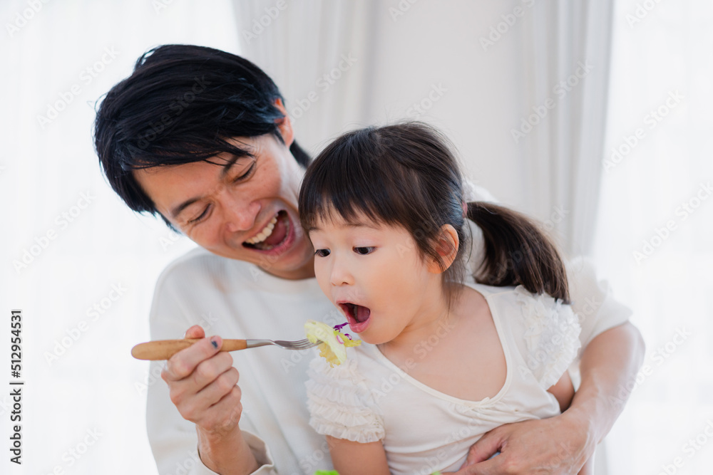 パパと一緒にご飯を食べる小さな女の子