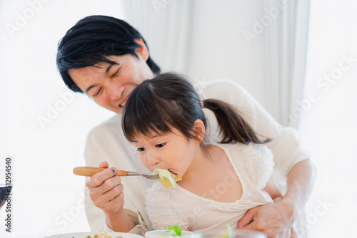 パパと一緒にご飯を食べる小さな女の子