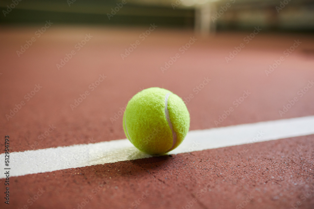Close-up of small yellow ball for tennis game placed on baseline of court, sport and leisure concept