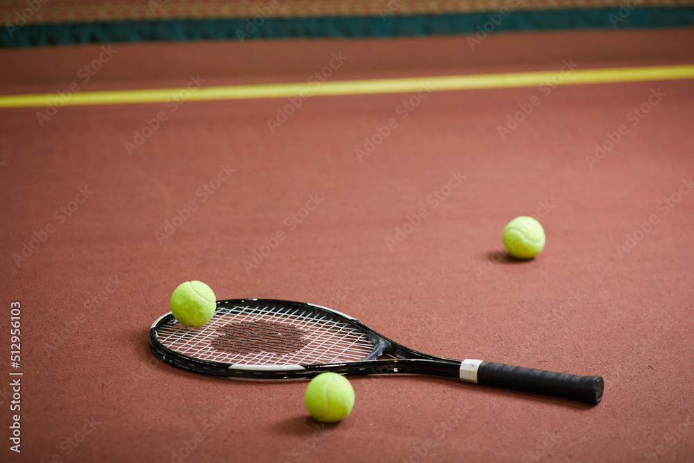 Close-up of modern tennis equipment scattered on floor of indoor tennis court, background of sports objects