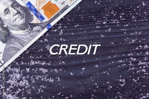 CREDIT - word (text) on a dark wooden background, money, dollars and snow. Business concept (copy space).