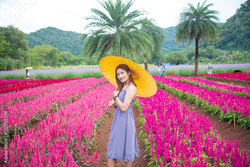 Asian woman traveling in a field of flowers at sunset
