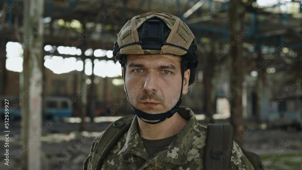 Portrait of fearless defender in safety helmet and uniform looking at camera with calm face while standing alone on destroyed abandoned plant. Brave hero, war and defence concept. Portrait of fearless defender in safety helmet and uniform looking at camera with calm face while standing alone on destroyed abandoned plant. Brave hero, war and defence concept.