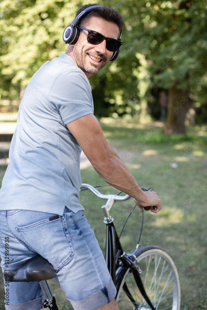 man in sun glasses smiling while cycling in the park