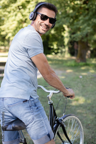 man in sun glasses smiling while cycling in the park © auremar
