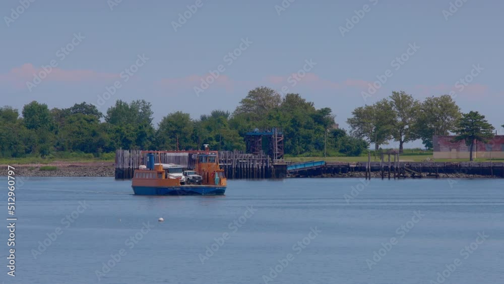 Orange Roll-on, roll-off ferry leaving the prison dock at Hart Island, with white prison bus. Blue sky on a sunny day. Orange Roll-on, roll-off ferry leaving the prison dock at Hart Island, with white prison bus. Blue sky on a sunny day.