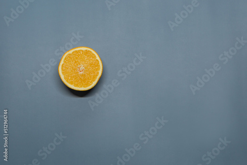 A ripe orange cut in half lies on a blue background