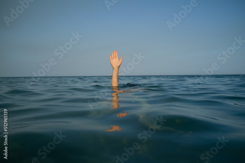 Man hand forearm coming out of water beach blue sea