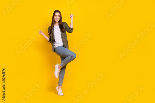 Full body photo of ecstatic overjoyed lady raise fists in victory win money in lottery giveaway isolated on yellow color background