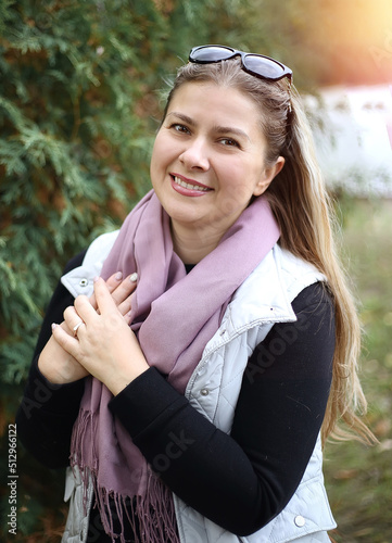 Young cute caucasian woman with smile looking at camera while resting in autumn forest. Women 35+. Nature and walks in the air. Joy concept
