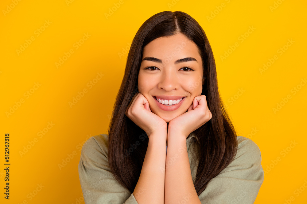 Portrait of young stunning asian girl lean her chin on her hands relaxing on weekend day isolated on yellow color background Portrait of young stunning asian girl lean her chin on her hands relaxing on weekend day isolated on yellow color background