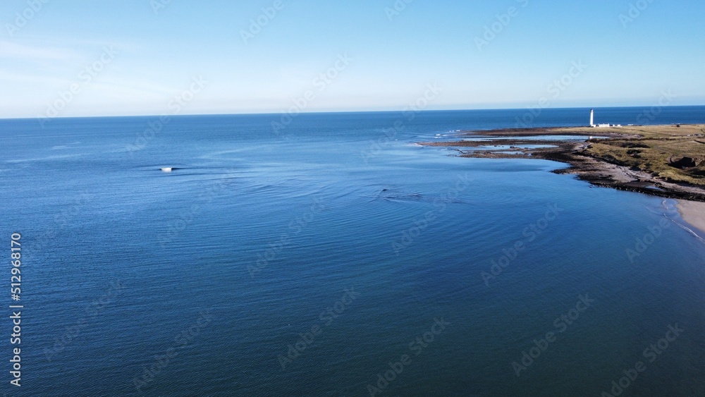 Aerial view of the incredible coastline of Scotland with views of the North Sea. Blue sky background with ocean waves. 