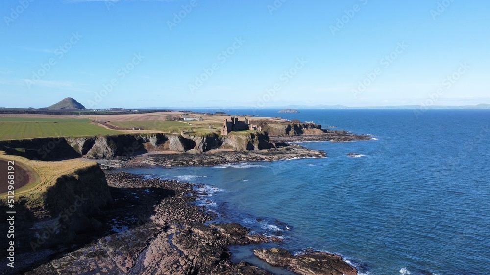 Aerial view of the incredible coastline of Scotland with views of the North Sea. Blue sky background with ocean waves. 