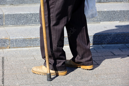 Old man with walking cane walking on the street. Concept of disability, limping senior adult