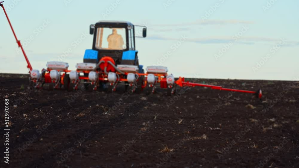 Red combine harvester plows the loose earth in field for planting new wheat on sunny summer day. Large plot farmland. Agricultural equipment for technical works. Production large volume of products. Red combine harvester plows the loose earth in field for planting new wheat on sunny summer day. Large plot farmland. Agricultural equipment for technical works. Production large volume of products.