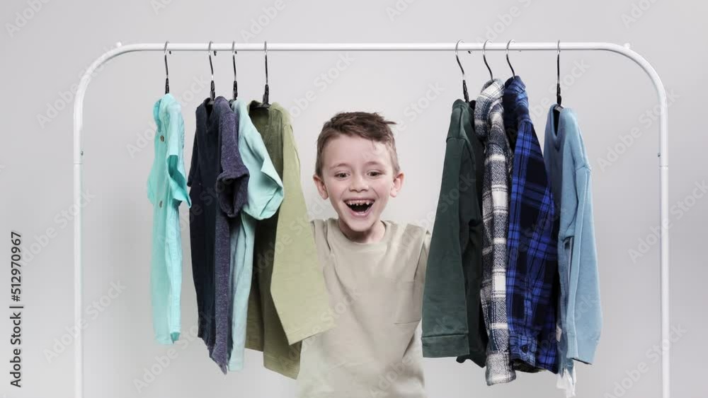 The little boy appears from behind the clothes rack. The boy looks ...