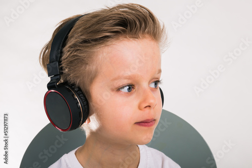 Beautiful kid boy in big headphones. A boy in a white t-shirt listening to music. copy space